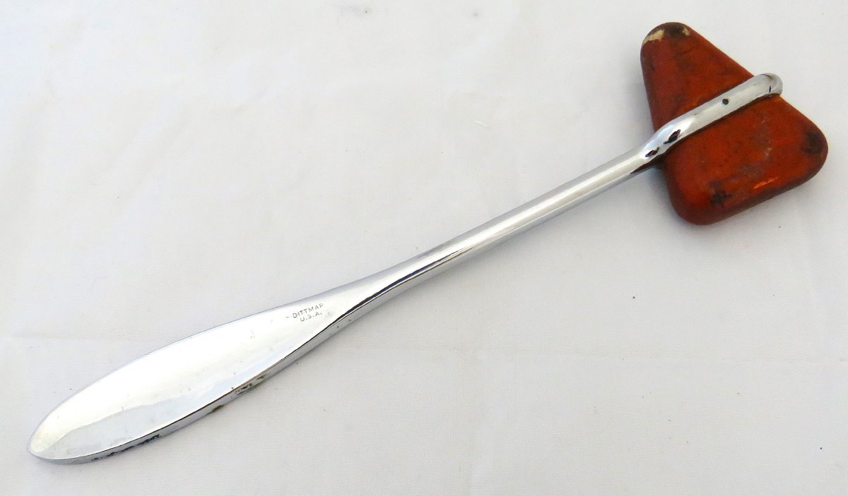 Reflex hammer with grey metal handle and triangular orange rubber head.